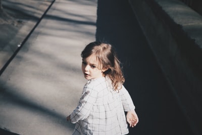 初学走路的女孩白天走在灰色的水泥路上